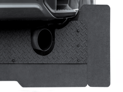 A textured gray mat with a diamond plate pattern under a vehicle's black exhaust pipe.