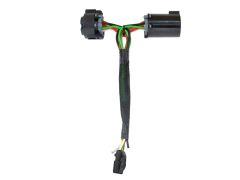 A vehicle wiring harness connector with two black plastic connectors and several colored wires (green, yellow, red, black) covered in protective sheathing.