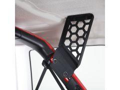 Close-up of a black, hexagon-patterned bracket mounted on a vehicle's white ceiling, with red trim visible nearby.