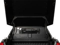 Open truck bed with a lifted black tonneau cover and visible hydraulic struts.