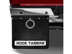 A black rubber mud flap with the brand name "ROCK TAMERS," secured to the rear of a truck, featuring a circular vent and multiple metal bolts.