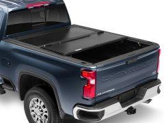 Rear view of a dark blue Chevrolet Silverado truck with a closed black tonneau cover, showcasing its prominent design and alloy wheels.
