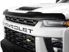 Close-up of a White Chevrolet vehicle's front, featuring a bold black grille with "CHEVROLET" in large letters and sleek headlights.