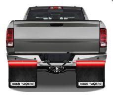 Rear view of a gray pickup truck with black mud flaps featuring "ROCK TAMERS" brand and red LED lights above them.