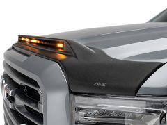 Close-up of a truck's hood with a black aerodynamic deflector featuring amber LED lights, against a metallic gray truck body.