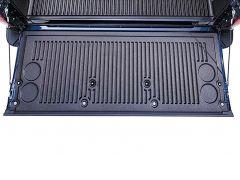 A black ribbed surface of a car tailgate with two circular depressions in the corners.