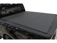 Top view of a black pickup truck bed with a textured tonneau cover featuring a diamond plate pattern.