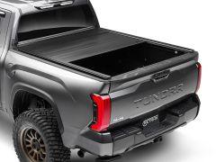 Rear view of a Toyota Tundra pickup truck, showcasing a partially closed retractable bed cover and bold red taillights.