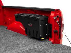 Red pickup truck bed with a black "Swing Case" storage box mounted on the side, resting on grey carpet-like material.