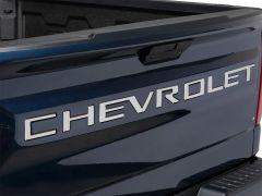 Rear view of a navy blue pickup truck tailgate featuring the word "CHEVROLET" in silver letters and a black camera above the latch.