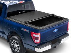 Blue Ford F-150 pickup truck with a partially open black tonneau cover, viewed from the rear.