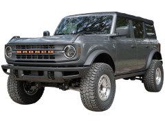 A gray Ford Bronco SUV with a black soft top and orange "BRONCO" lettering on its grille, parked in an outdoor setting.