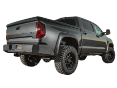 Rear view of a dark gray Toyota Tundra truck on a white background, showcasing its large off-road tires and sleek design.