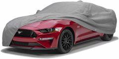 Red Ford Mustang car covered with gray protective cover.