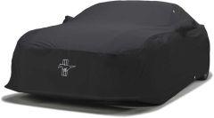 Car covered with black protective cover featuring white logo.