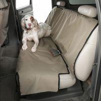 White dog with brown spots lying on car seat cover.