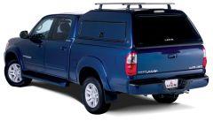 A blue Toyota Tundra pickup truck from the rear-left side, featuring a glossy camper top and silver alloy wheels.
