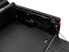 Open tailgate of a pickup truck showcasing a textured truck bed and storage compartments.