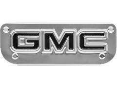 Silver emblem with raised black "GMC" letters, set against a metallic background with four screw holes.