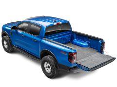 A vibrant blue pickup truck with rugged tires is shown from an overhead angle. The tailgate is open, revealing a spacious, carpeted truck bed.