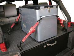 A portable refrigerator is secured in a vehicle's trunk with red straps, placed on a textured black platform.
