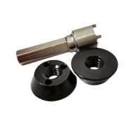 An assortment of mechanical components, including a metallic tool with a hexagonal end and two black, cone-shaped threaded pieces.