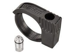 A black McGard locking wheel nut tool beside a metallic locking wheel nut, placed on a smooth metallic surface.